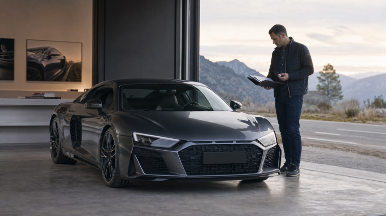 Acheteur consultant l’historique d’une supercar allemande grise à moteur central dans un showroom