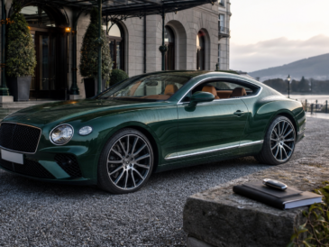 Grande GT britannique vert anglais devant un hôtel avec carnet d’entretien, évoquant une Bentley Continental GT W12 d’occasion