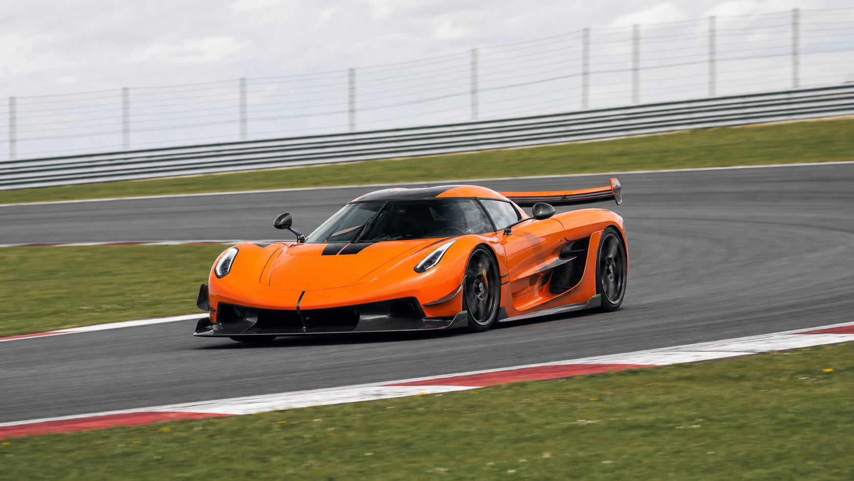 Hypercar orange à grand aileron en appui dans une courbe de circuit