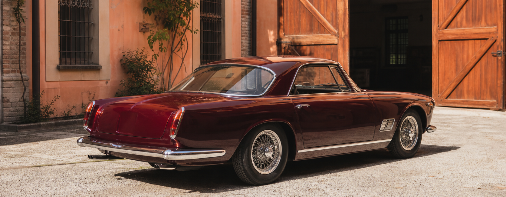 Maserati classique bordeaux dans une cour historique de Modène avant restauration