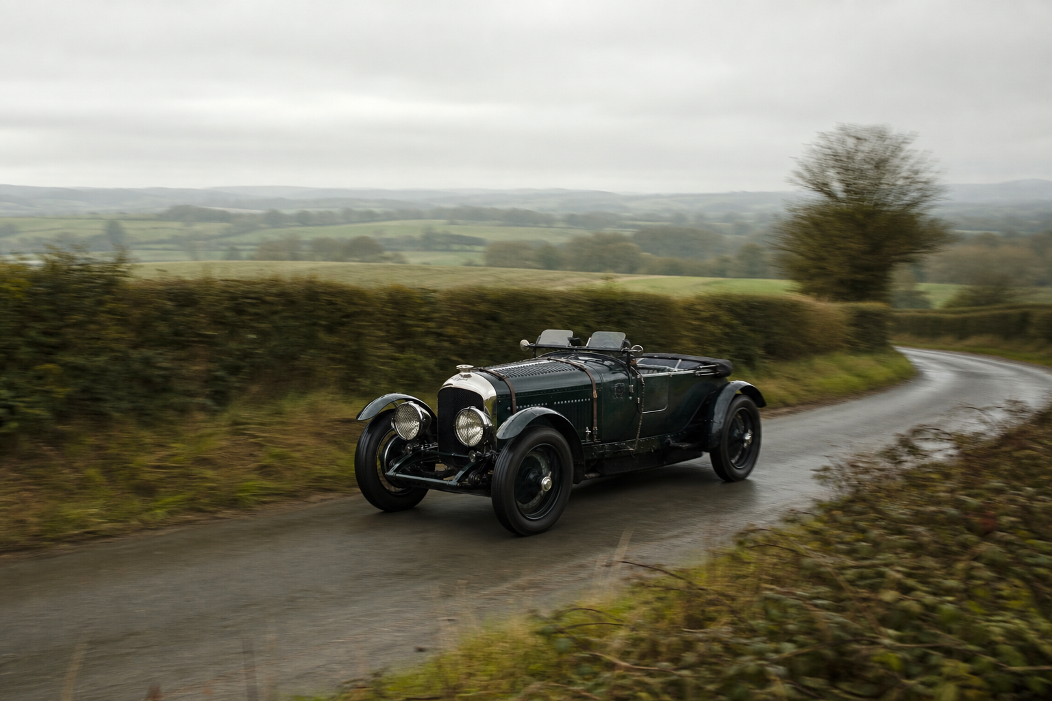 Bentley Speed Six Continuation verte roulant sur une route de campagne britannique humide