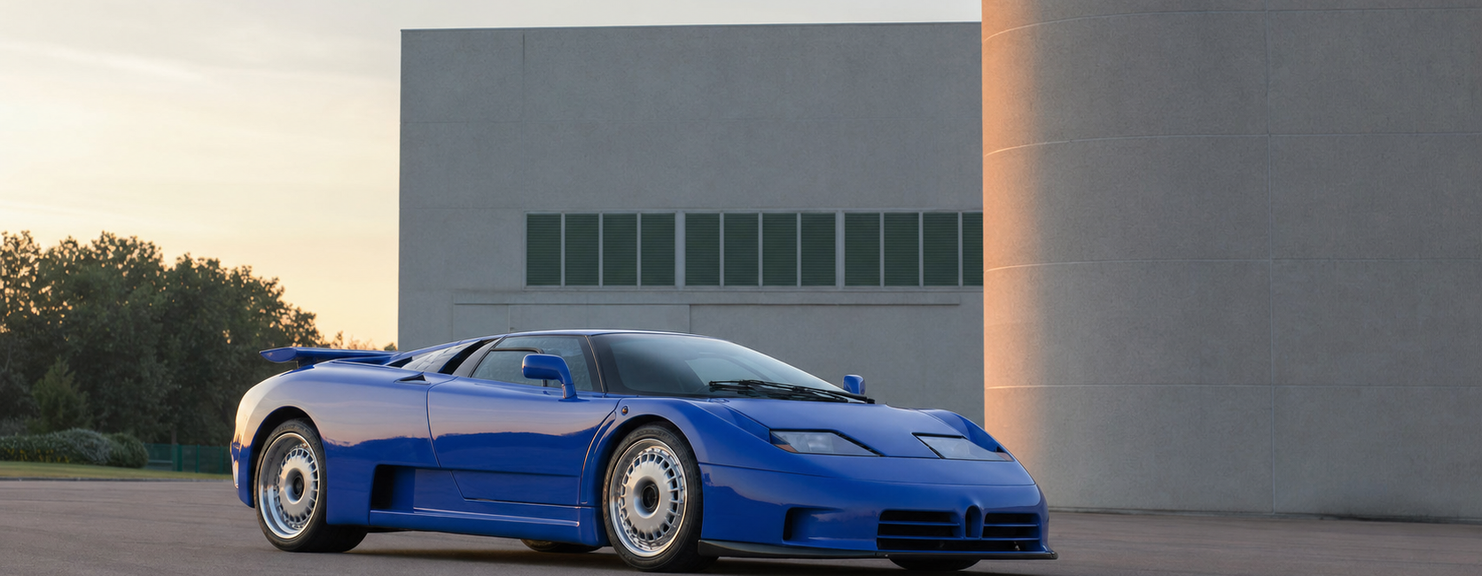 Hypercar bleue des années 1990 devant une architecture industrielle italienne au lever du jour