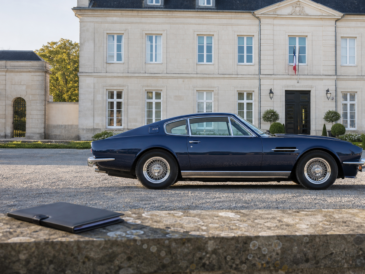 Automobile de collection bleu nuit devant un bâtiment administratif avec dossier fermé au premier plan