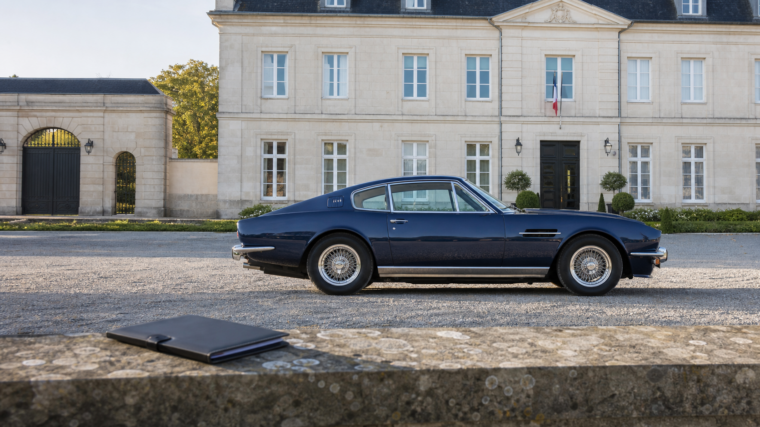 Automobile de collection bleu nuit devant un bâtiment administratif avec dossier fermé au premier plan