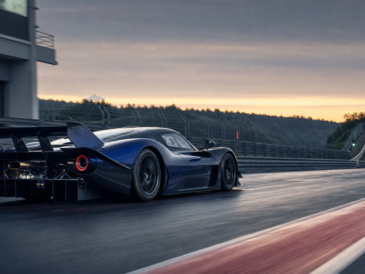 Hypercar de piste bleu nuit accélérant à la sortie des stands au lever du jour