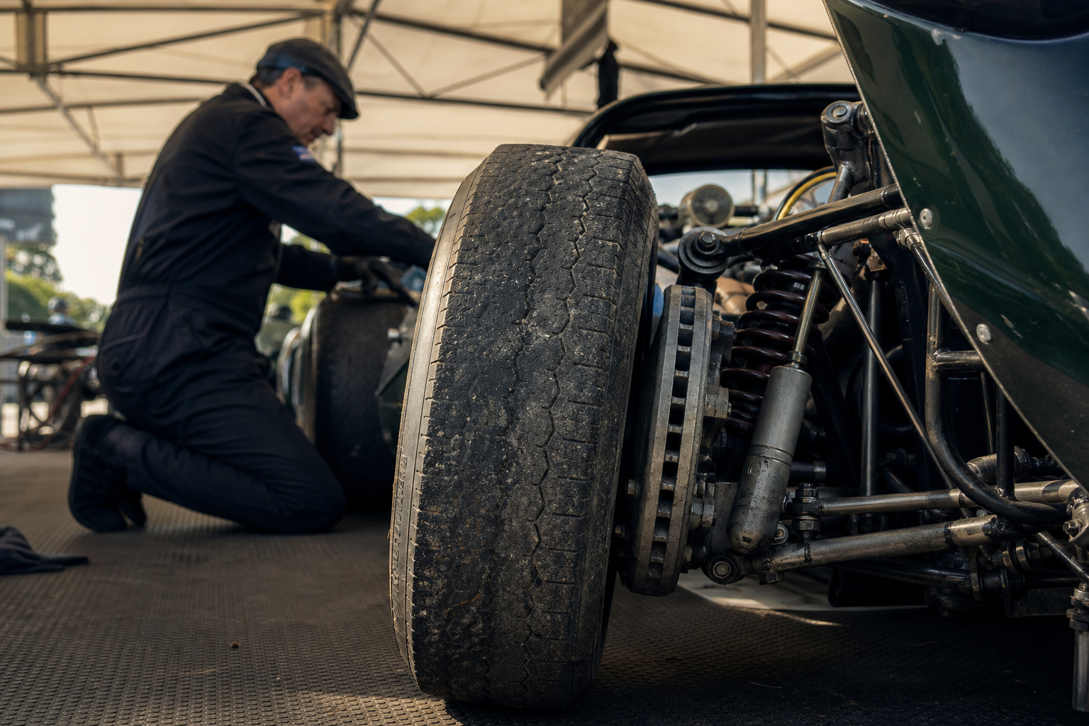 Spécialiste examinant les freins et la suspension d'une voiture de course historique dans un paddock