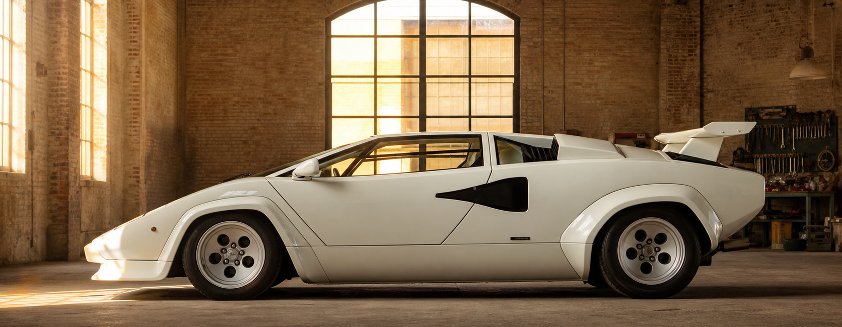 Lamborghini Countach blanche de profil dans un hangar italien en briques avant restauration