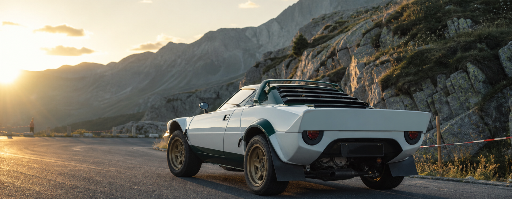 Coupé de rallye historique italien blanc et vert arrêté au lever du soleil dans un col alpin