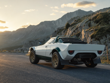 Coupé de rallye historique italien blanc et vert arrêté au lever du soleil dans un col alpin