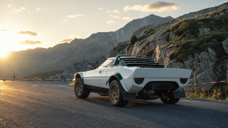 Coupé de rallye historique italien blanc et vert arrêté au lever du soleil dans un col alpin