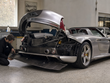 Supercar argentée inspectée en atelier avec panneaux carbone ouverts
