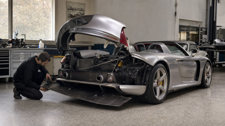 Supercar argentée inspectée en atelier avec panneaux carbone ouverts