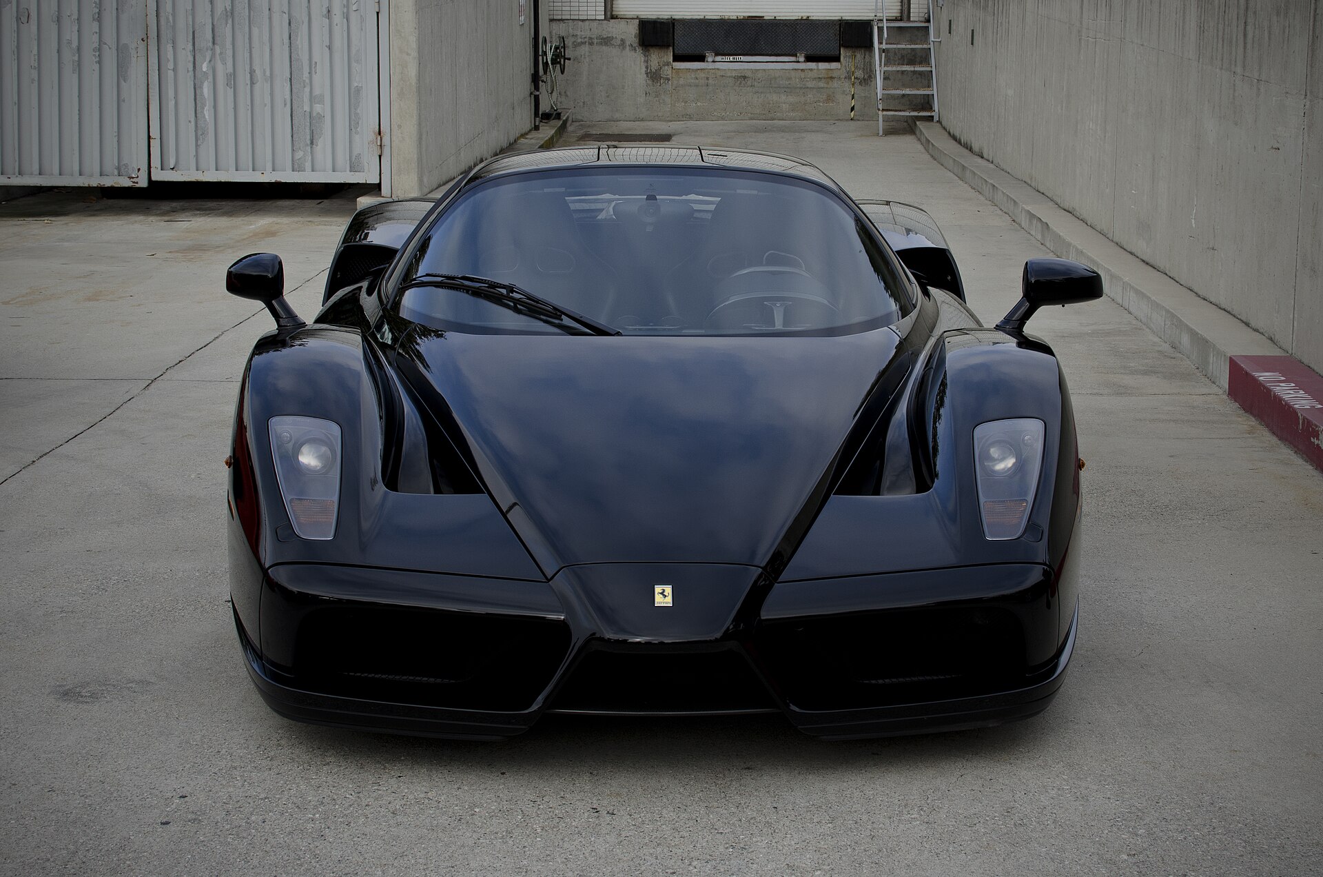 Ferrari Enzo noire vue de face sur une aire fermée
