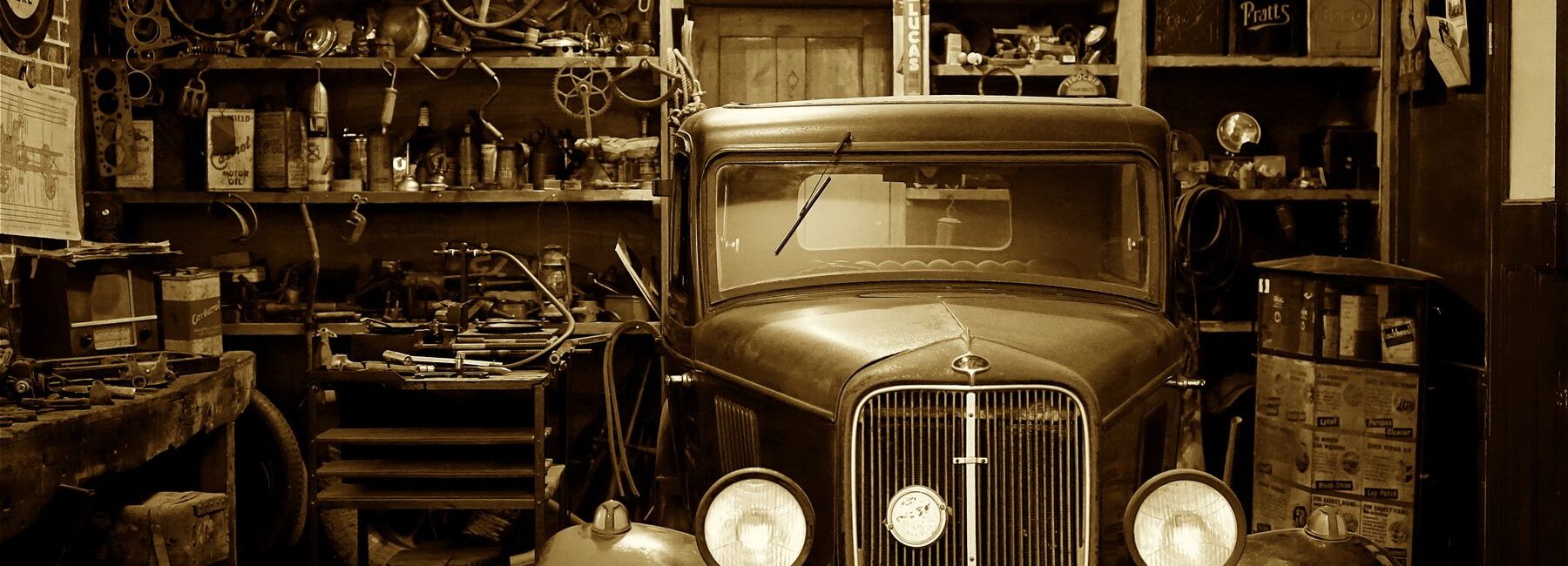 Voiture ancienne immobilisée dans un garage rempli de pièces et d’outils