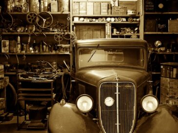 Voiture ancienne immobilisée dans un garage rempli de pièces et d’outils