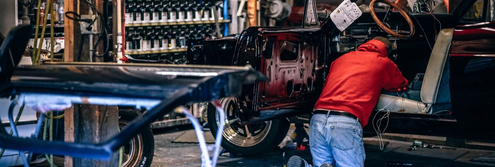 Technicien travaillant sur une voiture ancienne démontée dans un atelier de carrosserie