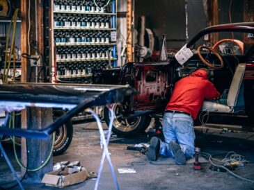 Technicien travaillant sur une voiture ancienne démontée dans un atelier de carrosserie