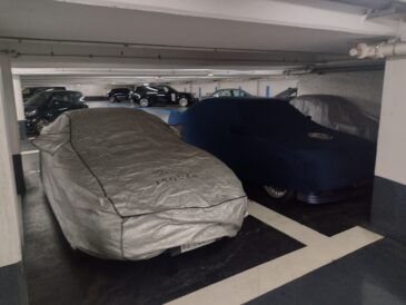 Deux voitures sous housse stationnées côte à côte dans un garage