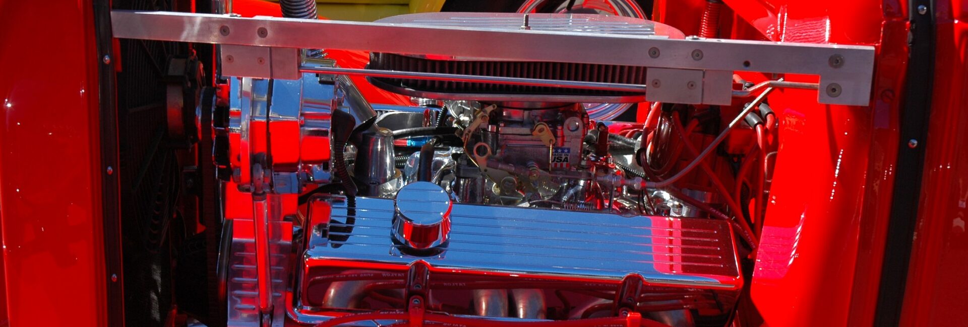 Compartiment moteur rouge d’une voiture ancienne avec radiateur et durites visibles