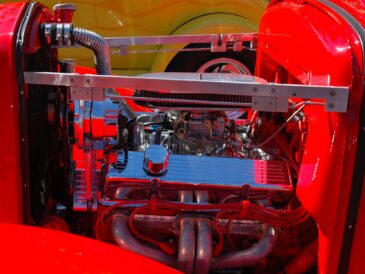 Compartiment moteur rouge d’une voiture ancienne avec radiateur et durites visibles