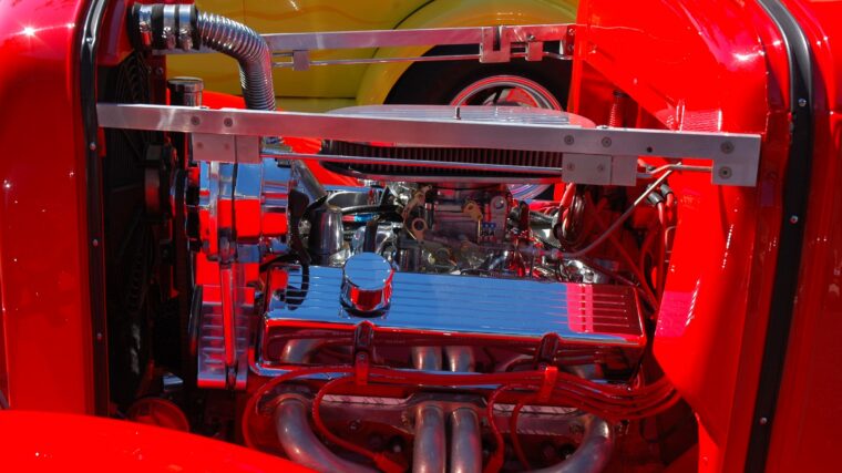 Compartiment moteur rouge d’une voiture ancienne avec radiateur et durites visibles