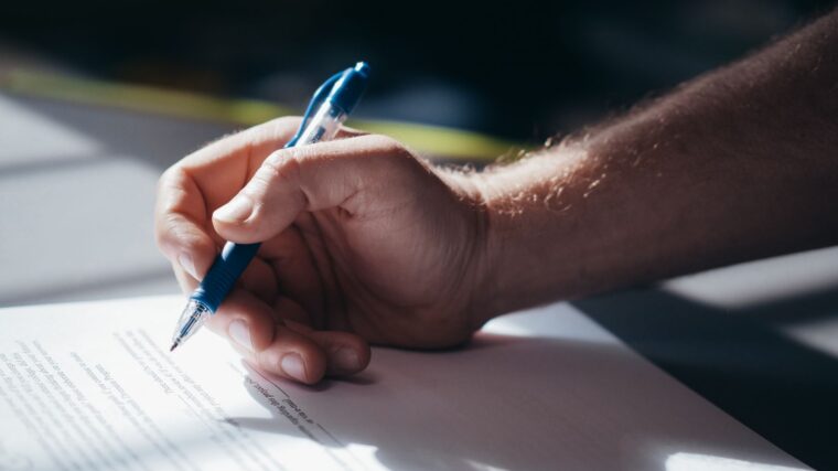 Main signant un document pour préparer la transmission d’une voiture de collection