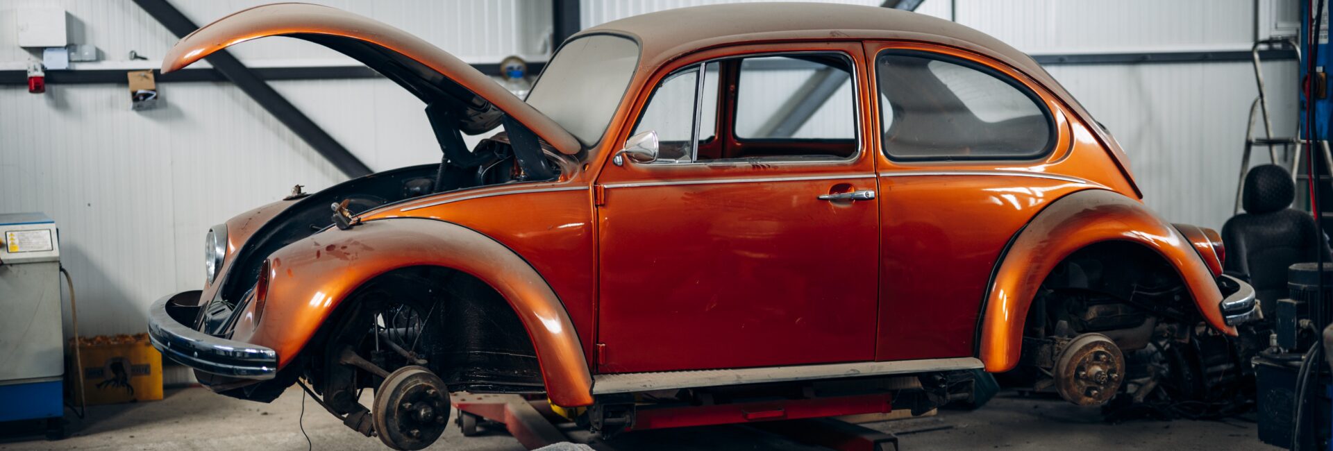 Voiture ancienne orange sur un pont dans un atelier automobile