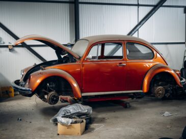 Voiture ancienne orange sur un pont dans un atelier automobile
