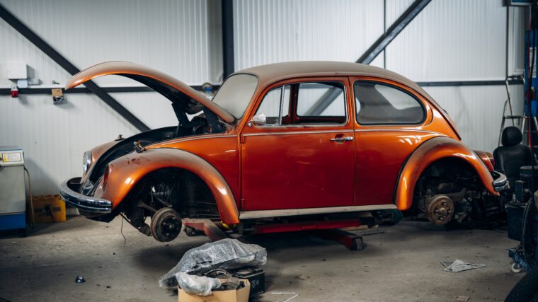 Voiture ancienne orange sur un pont dans un atelier automobile