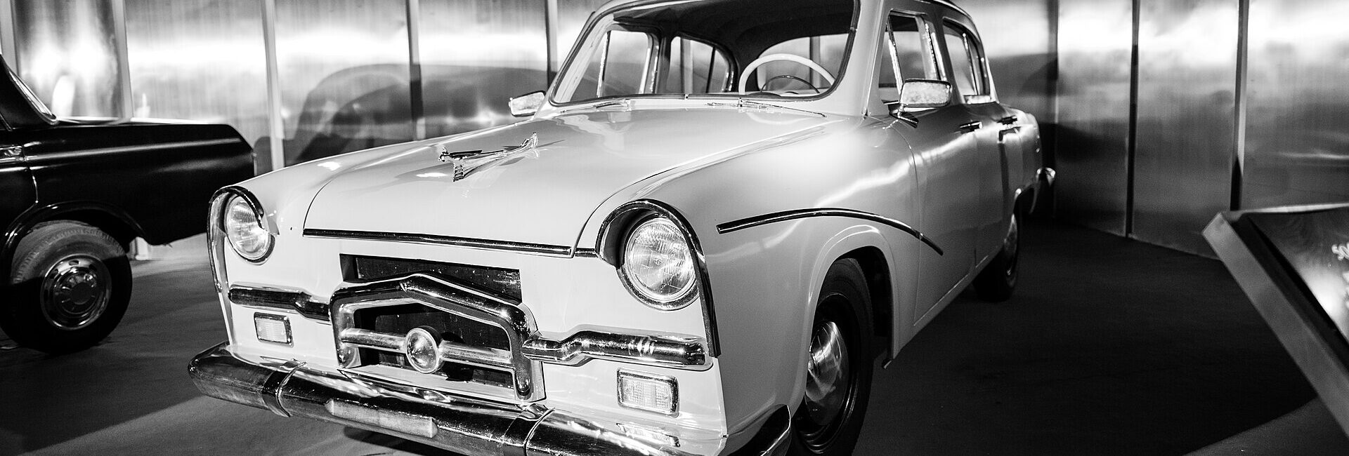 Voiture ancienne noire et blanche exposée dans un showroom automobile